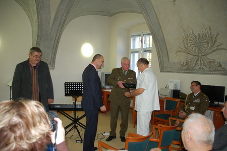 Ředitel Vojenské nemocnice Olomouc plukovník MUDr. Lubomír Dobeš a primář Léčebny dlouhodobě nemocných VN Olomouc MUDr. Lóránt Görcs přebírají věcné dary od tajemníka Československé obce legionářské a ředitele projektu péče o válečné veterány Petra Hozlára a uměleckého vedoucího Vojenského uměleckého souboru Ondráš Čestmíra Komárka