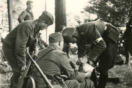 Vojenští zdravotníci ošetřují vojína, jenž utrpěl zranění v boji se sudetoněmeckými teroristy (Vojenský ústřední archiv – Vojenský historický archiv)