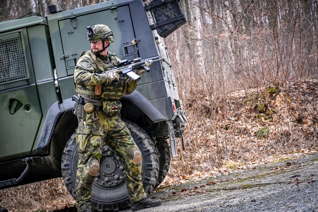 Jakmile výstřely neznámých útočníků utichnou,  vojáci nasedají do vozidla a odjíždějí bezpečnou cestou pryč
