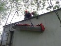 Záchranáři spouští zraněného ze střechy domu