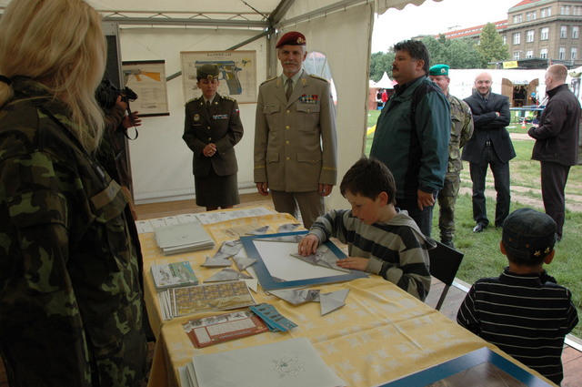 Generál Petr Pavel sleduje, jak malý návštěvník staví puzzle s armádní tematikou