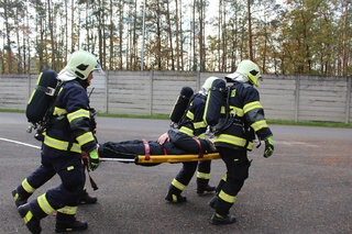 Raněný je transportován do bezpečné vzdálenosti od hořící budovy