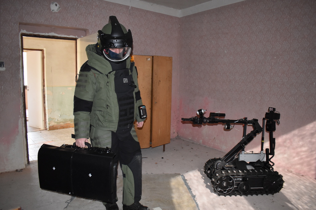 pyrotechnik v obleku EOD 10 a robot Talon při výcviku