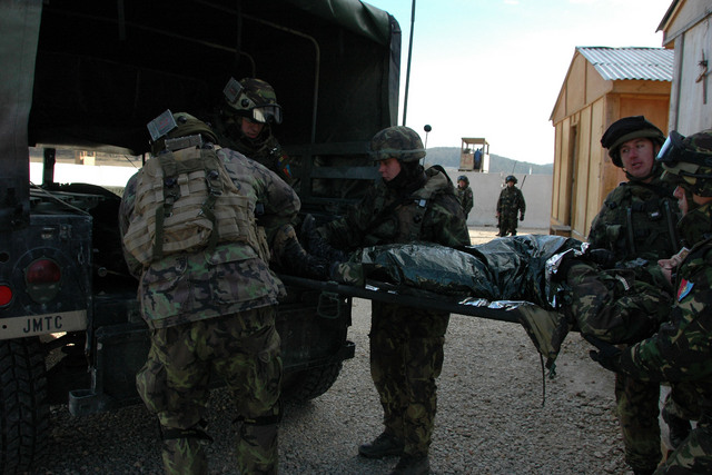 Vojáci společně nakládají své kolegy do aut - čeká je přeprava vrtulníkem