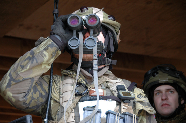 Příslušník 4. OMLT pozoruje pohyb v lese dalekohledem