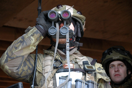 Příslušník 4. OMLT pozoruje pohyb v lese dalekohledem