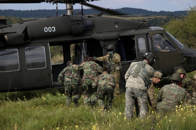Člen posádky vrtulníku Black Hawk dává pokyn k nasednutí. 