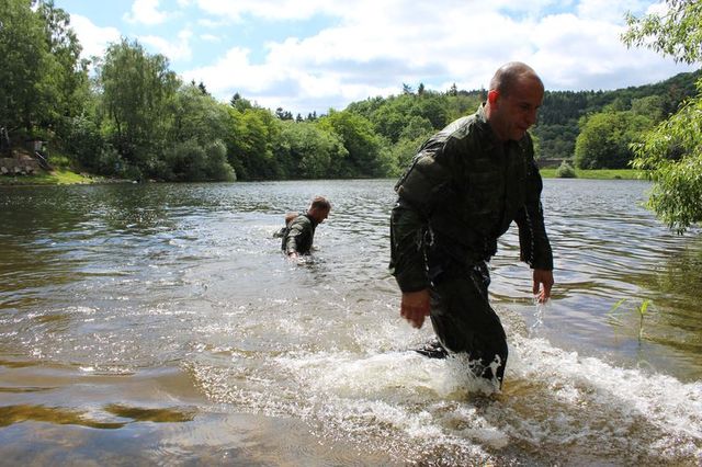 Soutěžící po překonání vodního toku plaváním